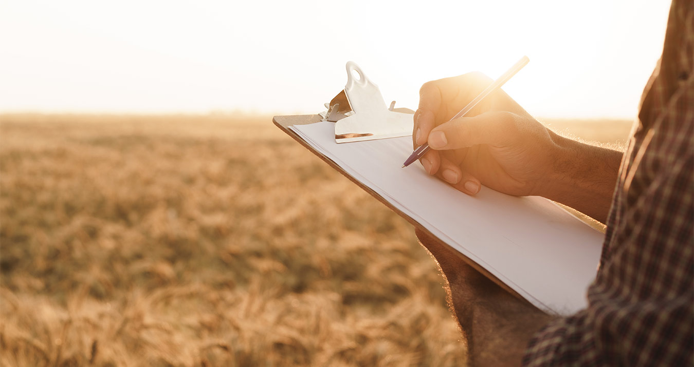 close-up of a person writing on a clipboard in a field